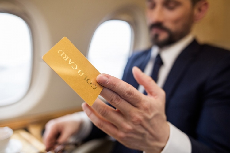 Hombre de negocios sentado en un avión privado con tarjeta de crédito en la mano.