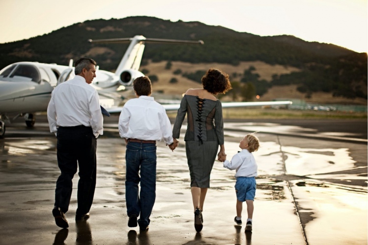 Familia caminando hacia un jet privado tomados de la mano.