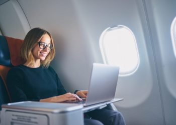 Mujer que trabaja en su computadora portátil mientras dentro del avión