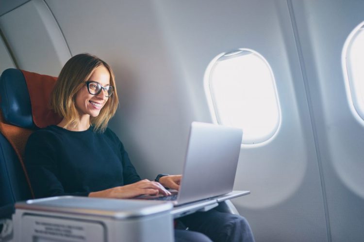 Mujer que trabaja en su computadora portátil mientras dentro del avión