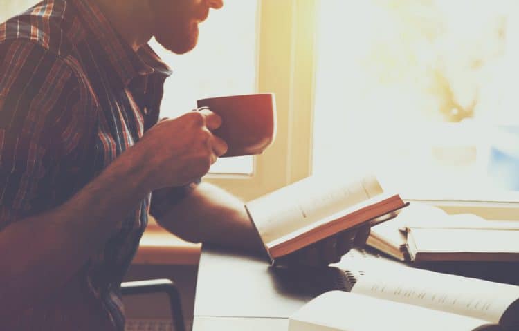 Hombres leyendo un libro con taza de café