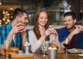 Amigos con teléfonos inteligentes cenando en un restaurante