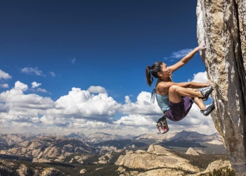 Mujer escaladora cuelga del borde de un desafiante acantilado