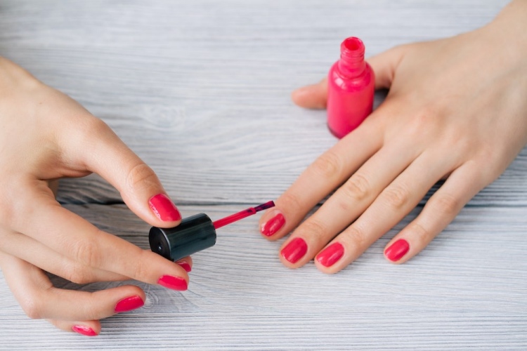 Mujer pintando sus uñas con laca roja