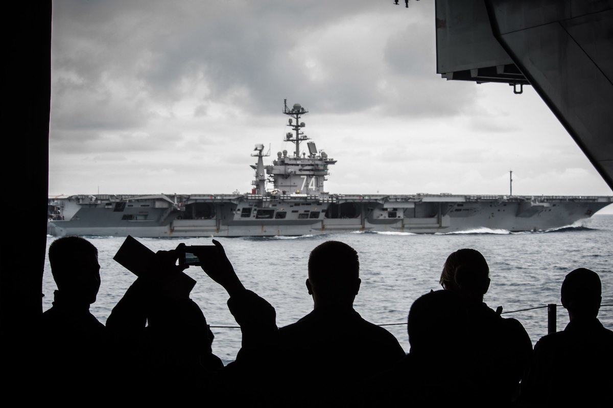 Los marineros observan el USS John C. Stennis que navega junto al USS Ronald Reagan.