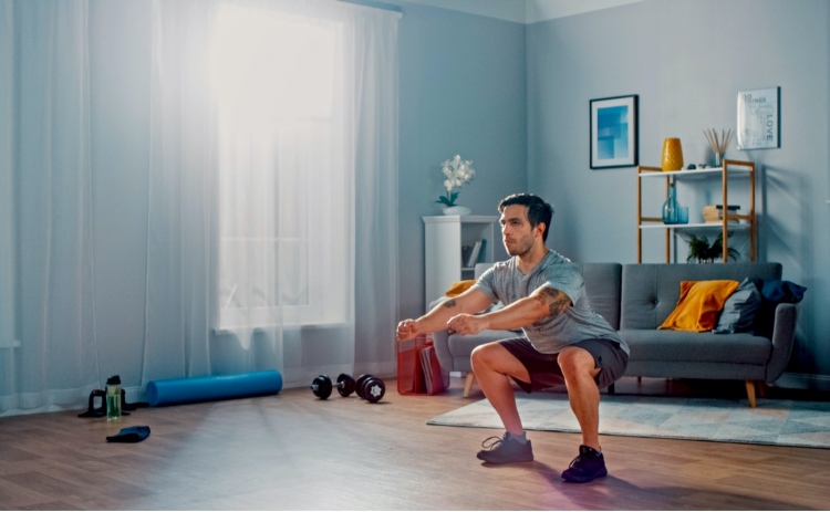 Hombre atlético haciendo ejercicios de sentadillas en casa