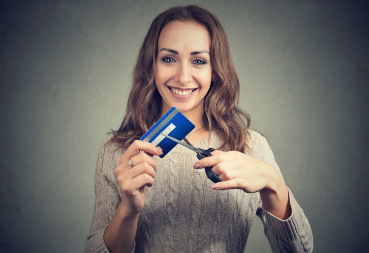 Mujer alegre que corta tarjetas de crédito después de pagar su deuda.