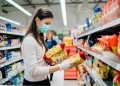 Mujer con mascarilla comprando comida en el supermercado.