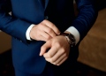 Hombre de negocios en traje y ajusta su reloj, preparándose para una reunión.