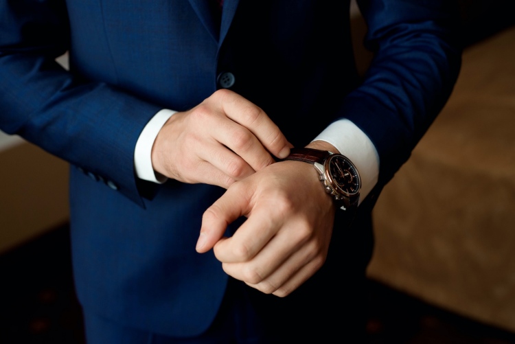 Hombre de negocios en traje y ajusta su reloj, preparándose para una reunión.
