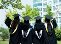 Mujeres graduadas con toga y birrete de graduación en el campus.
