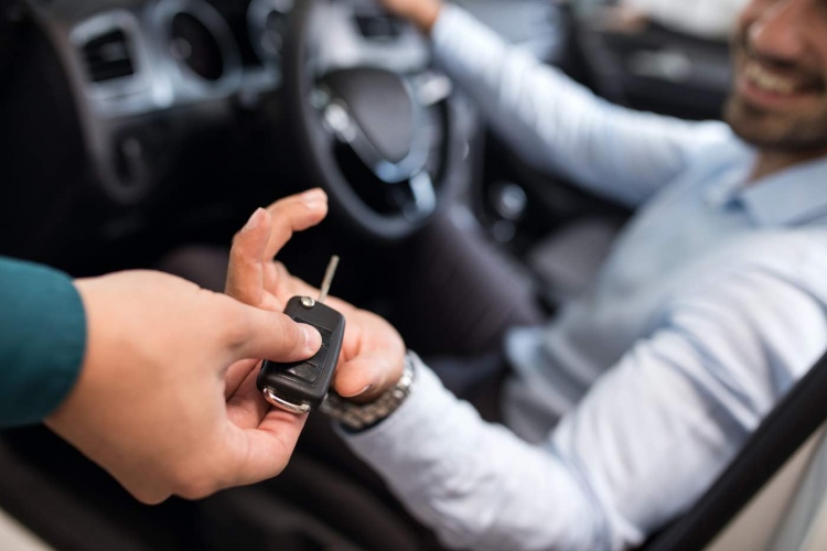 Hombre sentado en un coche y recibiendo las llaves del auto