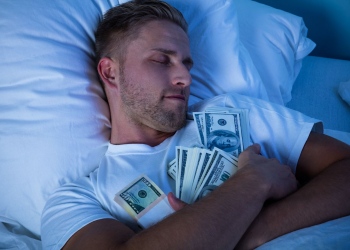 Hombre durmiendo en la cama con paquete de dólares
