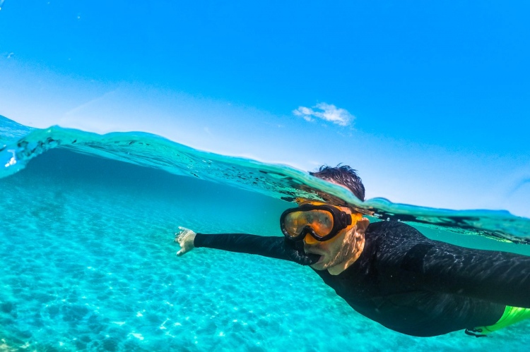 Hombre buceando en aguas turquesas y descubriendo el mundo bajo el mar