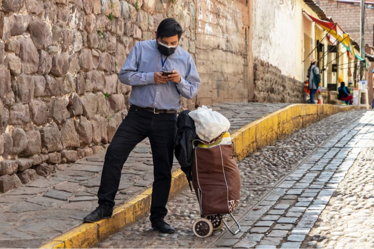 Empresario con máscara y teléfono móvil durante la pandemia de coronavirus covid-19 en Cusco, Perú en América del Sur.