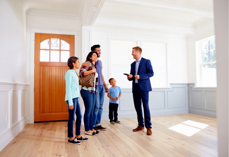 Agente inmobiliario mostrando alrededor de casa nueva a una familia.