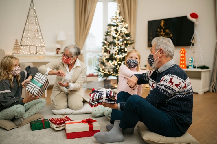 Familia disfrutando fiestas navideñas en casa, saludos de codo por Covid-19.