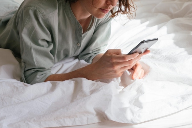 Mujer usando un teléfono inteligente en la cama