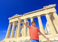 Niño feliz tomando una fotografía delante del Partenón de Atenas, Grecia.