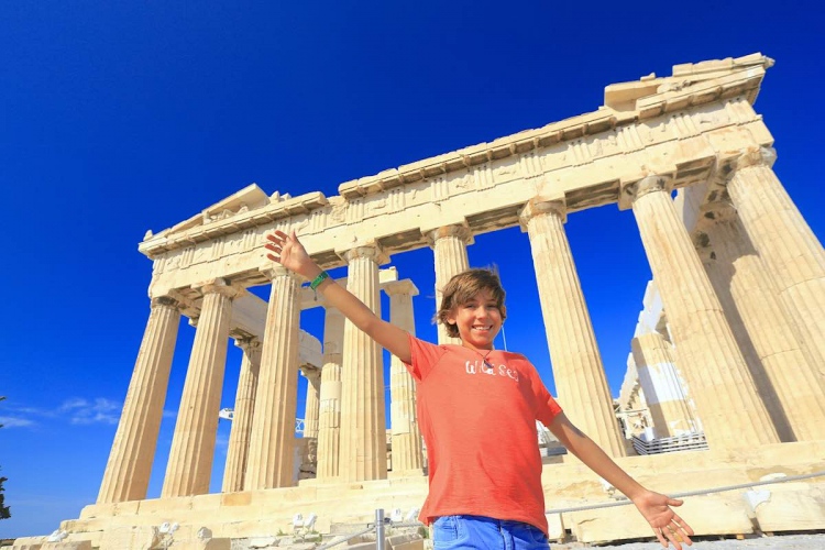 Niño feliz tomando una fotografía delante del Partenón de Atenas, Grecia.