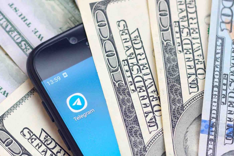 Teléfono inteligente con aplicación Telegram y muchos billetes de cien dólares.