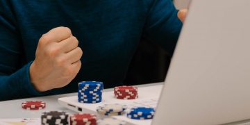 Joven jugando con su computadora en sitios web de apuestas. ruleta de póquer de casino en línea.
