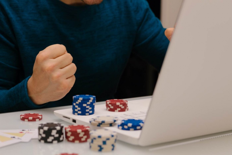 Joven jugando con su computadora en sitios web de apuestas. ruleta de póquer de casino en línea.