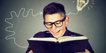 Hombre joven con gafas leyendo libro se le ocurre una idea