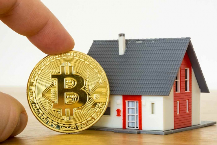 Moneda Bitcoin y un modelo de casa.