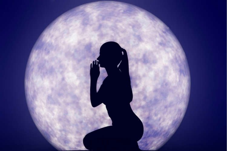 Silueta de una mujer pidiéndole al Universo frente a la luna llena.