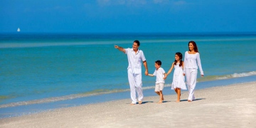 Familia feliz divirtiéndose en la arena de una playa soleada.