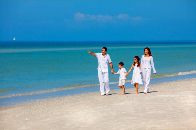 Familia feliz divirtiéndose en la arena de una playa soleada.