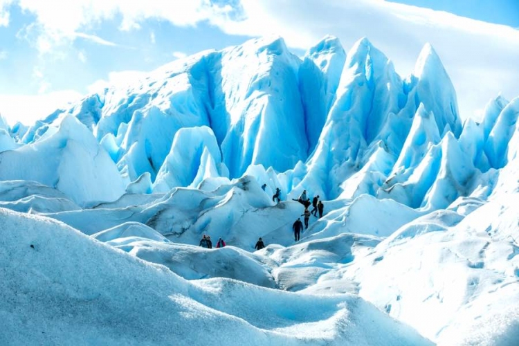Caminata de visitantes entre las capas de formación de hielo nevado del Glaciar Perito Moreno