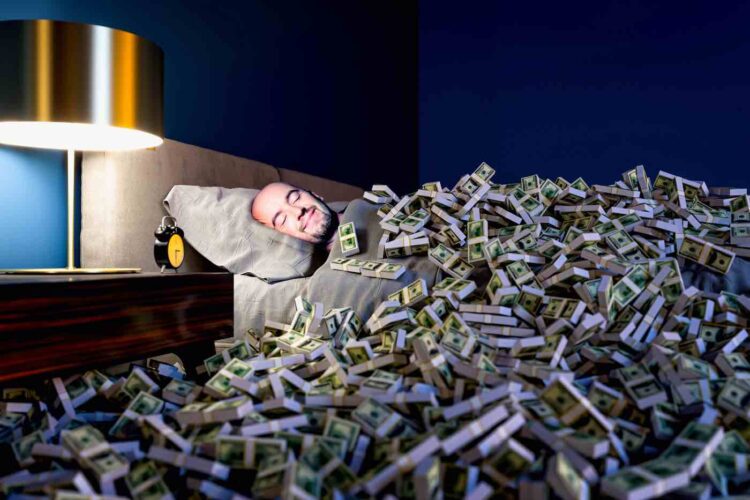 Hombre durmiendo en una cama cubierta de dinero en dólares. concepto de riqueza.